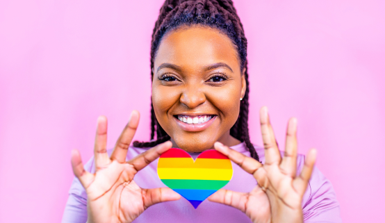 A person joyfully holding a rainbow pride heart